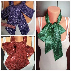 May include: Three sequined bow ties in different colors: purple, green, and burgundy. The bow ties are made of small, shiny sequins and are tied around a mannequin's neck.