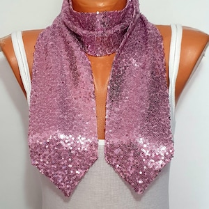 May include: A mauve scarf completely covered in small, reflective sequins. The scarf features a long, rectangular shape with pointed ends that drape downward. The fabric is densely embellished with shimmering, circular sequins in a consistent mauve tone.