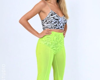 May include: A two-piece outfit consisting of a cropped camisole top with a black and white swirling marble pattern and thin straps, paired with high-waisted, neon yellow sheer flared trousers featuring a subtle tonal swirling pattern.