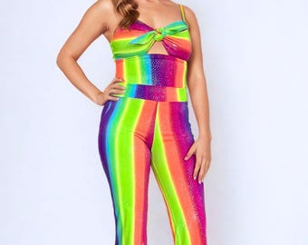 May include: A vibrant, rainbow-striped jumpsuit with a matching top. The top features a knotted detail at the bust and a keyhole cutout. The flared pants and top are in shades of red, orange, yellow, green, and purple.