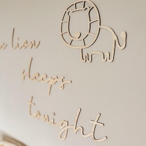 May include: Wooden wall decor with the text "The lion sleeps tonight" and a cutout of a lion with a mane.