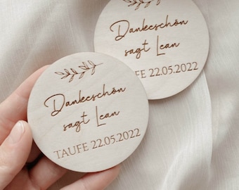 Può includere: Due cartelli rotondi in legno con un design a ramo frondoso e il testo "Danke schön sagt Lean" con le date "TAUFE 22.05.2022" e "FE 22.05.2022".