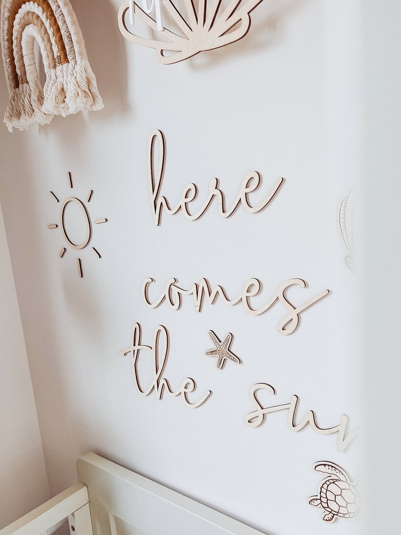 May include: Wooden wall decor with the words "here comes the sun" in a cursive font. The decor also includes a sun, a starfish, a seashell, and a turtle.