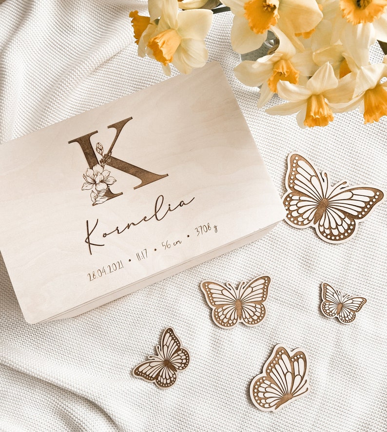 Peut inclure: Une bo&icirc;te &agrave; souvenirs en bois avec un motif floral et la lettre K, grav&eacute;e du nom "Kornelia" et de la date "26.04.2021". La bo&icirc;te comprend &eacute;galement l'heure "11:17", la longueur "56 cm" et le poids "3708 g".