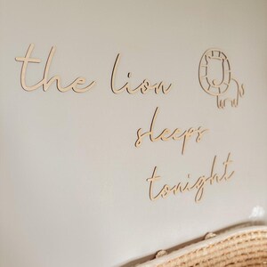 May include: Wooden wall decor with the words "the lion sleeps tonight" and a cutout of a lion's head.