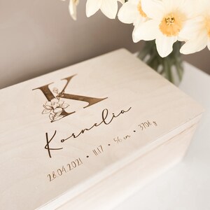 Peut inclure: Une bo&icirc;te &agrave; souvenirs en bois clair avec une inscription personnalis&eacute;e. L'inscription indique "K" avec un motif floral, "Kornelia", "28.04.2021", "11:17", "56 cm" et "3708 g".