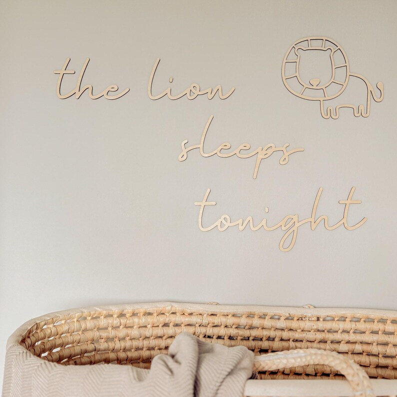 May include: Wooden wall decor with the phrase "the lion sleeps tonight" in a cursive font. The decor includes a cutout of a lion's head and body.