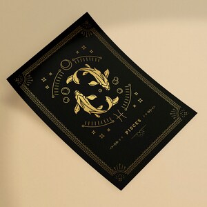 May include: A black and gold print with a stylized illustration of two fish, the astrological symbol for Pisces, and the word "Pisces" in gold lettering.