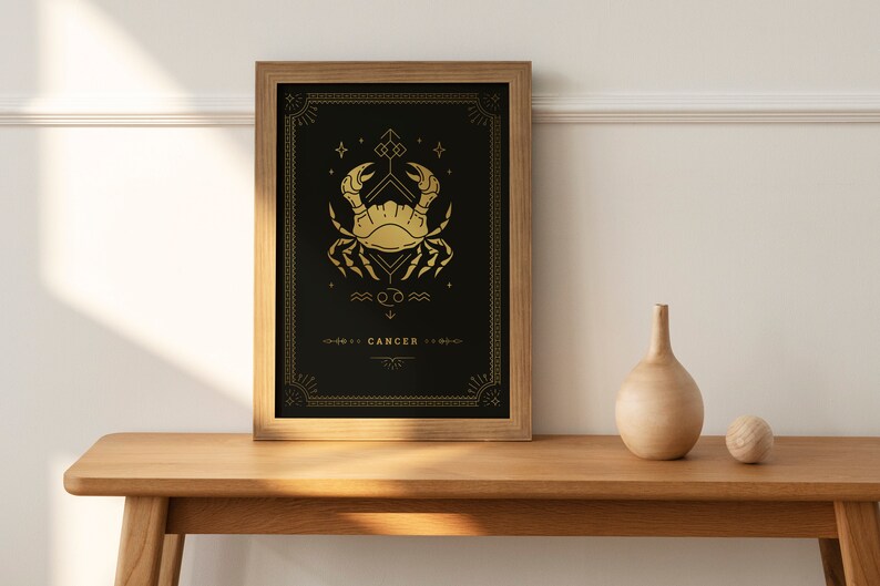 May include: A framed print with a gold design of the Cancer zodiac sign, a crab, on a black background. The text "Cancer" is at the bottom of the print.