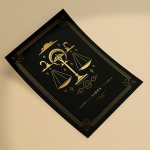 May include: Black rectangular card with a gold Libra zodiac design. The design features a scale, crescent moon, stars, and the word "LIBRA". The card has a decorative gold border and is set against a neutral background.