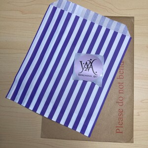 May include: A purple and white striped paper bag with a sticker that says "Webluminal Art" on a brown cardboard envelope. The envelope has the text "Please do not bend" printed on it.