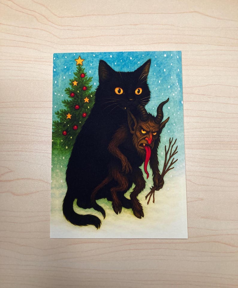 May include: A whimsical illustration depicts a black cat holding a Krampus-like figure. A small Christmas tree with red ornaments and a star sits to the left. The background is a snowy scene with a blue sky.