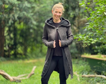 Op de afbeelding: Een lange, grijze hooded cardigan met een zilveren sluiting. De cardigan is gemaakt van een zacht, pluche materiaal en heeft een ontspannen pasvorm.