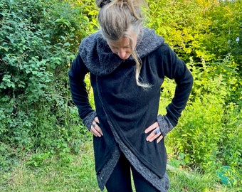 Op de afbeelding: Een zwarte hoodie met grijze bies. De cardigan is om het lichaam gewikkeld en heeft een lange, vloeiende stijl.