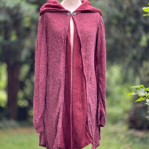 Op de afbeelding: Een bordeauxrode hooded cardigan met een zilveren knoopsluiting. De cardigan is gemaakt van een zachte, gebreide stof en heeft een ontspannen pasvorm.