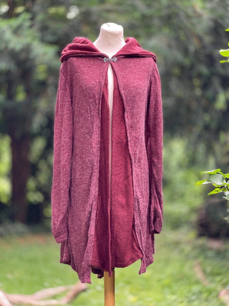 Op de afbeelding: Een bordeauxrode hooded cardigan met een zilveren knoopsluiting. De cardigan is gemaakt van een zachte, gebreide stof en heeft een ontspannen pasvorm.