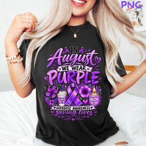 Peut inclure: Un t-shirt noir avec un motif portant le texte In August We Wear Purple, Overdose Awareness, Saving Lives, One Story At A Time. Le design comprend un ruban de sensibilisation violet, un papillon, une tasse à café, une fleur et une bougie.