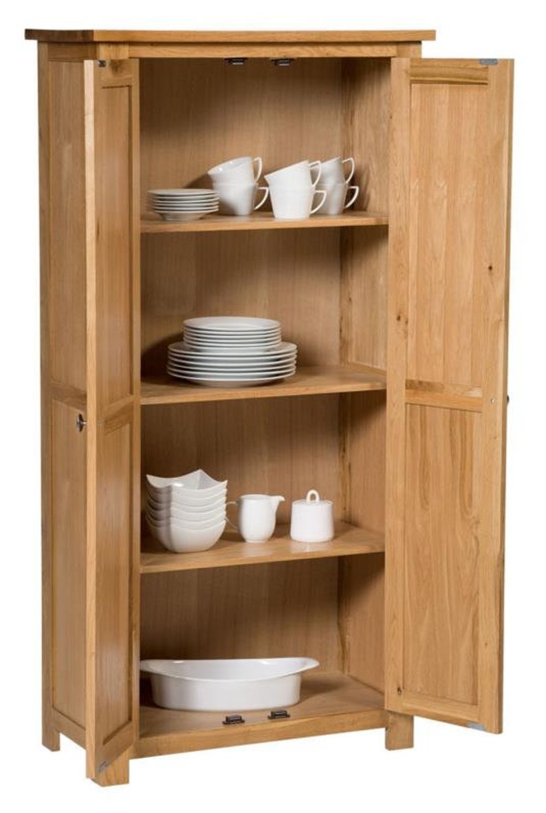 Puede incluir: Un armario de madera con dos puertas, abierto para revelar estantes llenos de platos y tazas blancas. El armario est&aacute; hecho de madera clara y tiene un dise&ntilde;o sencillo.