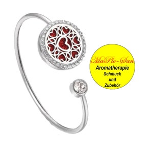 Peut inclure: Bracelet argenté avec un pendentif rond rouge et blanc en forme de cœur. Le pendentif est entouré de strass transparents. Le bracelet est terminé par un strass transparent.