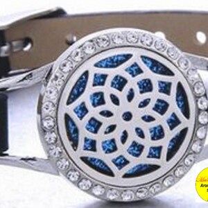 May include: A silver aromatherapy diffuser bracelet with a blue and white snowflake design. The bracelet has a black leather band with silver snaps.