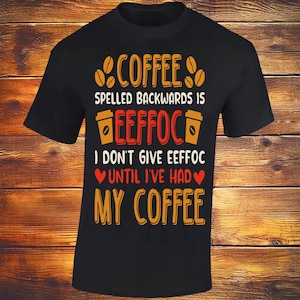 May include: Black t-shirt with a coffee-themed design. The text reads "Coffee spelled backwards is Eeffoc. I don't give eeffoc until I've had my coffee" in orange, red, and white. Coffee beans and coffee cup graphics are included.