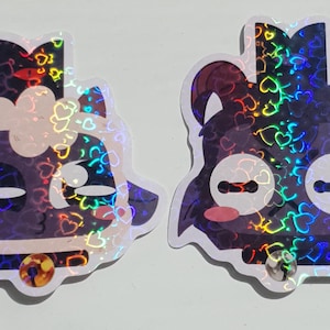 Pu&ograve; includere: Due adesivi olografici iridescenti con personaggi dei cartoni animati. Il primo adesivo &egrave; una pecora in bianco e nero con una corona e un collare dorato. Il secondo adesivo &egrave; un cane nero con una corona e un naso rosa.