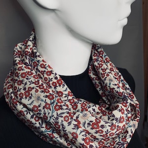 May include: A white scarf with a red and blue floral pattern. The scarf is made of a soft, lightweight fabric and is perfect for adding a touch of color to any outfit.