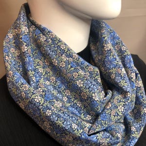 May include: A blue and white floral infinity scarf. The scarf is made of a soft, lightweight fabric and is perfect for adding a touch of style to any outfit.