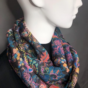 Pode incluir: Uma echarpe infinita preta com um padrão paisley colorido. O padrão apresenta cores rosa, azul, verde, amarelo e laranja.