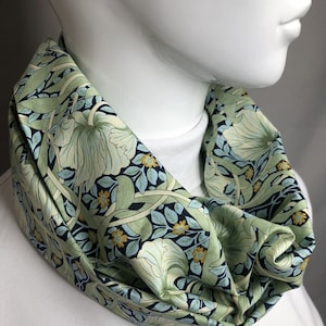 May include: A green and white floral patterned infinity scarf. The scarf is made of a soft, comfortable fabric and features a repeating pattern of flowers and leaves.
