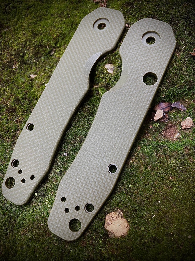 May include: Two green, textured, metal scales for a pocket knife. The scales have multiple holes and a rounded shape.