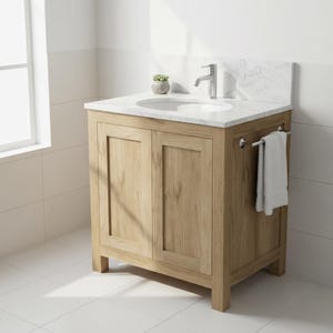 May include: A light oak bathroom vanity with a white marble countertop and a white oval sink. The vanity has two doors and a towel bar. A small potted plant sits on the countertop. A white towel hangs on the bar.