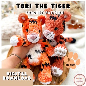 Könnte beinhalten: Zwei gehäkelte Tiger-Plüschtiere in Orange, Schwarz und Weiß. Der Text "TORI THE TIGER CROCHET PATTERN" steht oben. Die Worte "DIGITAL DOWNLOAD" stehen unten. Die Plüschtiere haben eine rosa Nase und schwarze Augen. Die Plüschtiere liegen auf einem Holztablett.