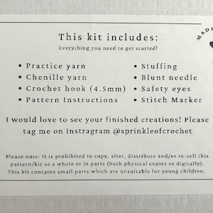 May include: A white card with black text listing the contents of a crochet kit. The text reads "This kit includes: Everything you need to get started!" and lists the following items: "Practice yarn", "Chenille yarn", "Crochet hook (4.5mm)", "Pattern Instructions", "Stuffing", "Blunt needle", "Safety eyes", and "Stitch Marker". The card also includes the text "MADE WITH LOVE" in a heart shape.