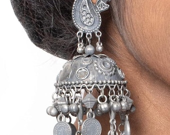 May include: Silver-toned dangle earrings with a paisley design at the top and a bell-shaped bottom. The earrings feature multiple dangling charms, including small coins and beads, creating a detailed and ornate appearance. The earrings are worn on the ear.