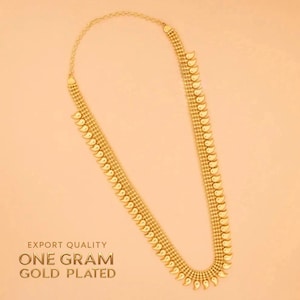 Pode incluir: Colar banhado a ouro com um design delicado. O colar apresenta uma série de pequenos pingentes em forma de gota ao longo do seu comprimento. O texto "EXPORT QUALITY ONE GRAM GOLD PLATED" é visível.
