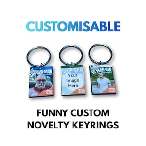 May include: Three novelty keyrings with silver-colored rings. Each keyring has a rectangular charm with a game box design. The keyrings have the text "CUSTOMISABLE" above them and "FUNNY CUSTOM NOVELTY KEYRINGS" below them.