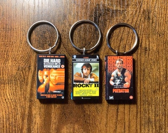 Miniatuur VHS Movie Keyring | ELKE film die je leuk vindt | Nieuwigheid 80s Actie films Gift Sleutelhanger | Geheime Kerstman | Verjaardagsfeestje Tassen | Charme