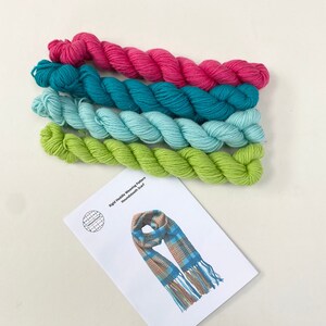 May include: A kit for a handwoven scarf with four skeins of yarn in shades of green, blue, and pink. The kit includes instructions for a "Rigid Heddle Weaving Pattern" for a "Houndstooth Scarf".