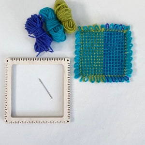 pinless pin loom with an example of a fabric square woven on the loom with balls of the wool used and tapestry needle.