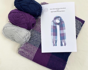 Op de afbeelding: Een knutselproject met een geweven sjaal in tinten paars, marineblauw en grijs. De afbeelding bevat drie bollen garen in bijpassende kleuren en een patroonblad met de titel "Plum, Navy and Grey Colourblock".