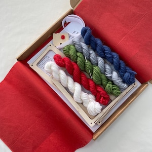 May include: A weaving kit with a wooden loom, a needle, and five skeins of yarn in red, white, green, gray, and blue.