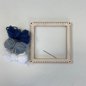 Blue grey and white yarn with a pinless pin loom and needle.