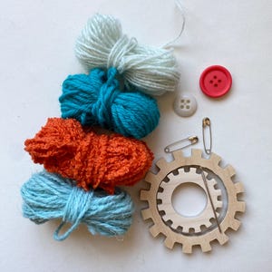 orange and turquoise yarn, wooden flower looms, needle and buttons