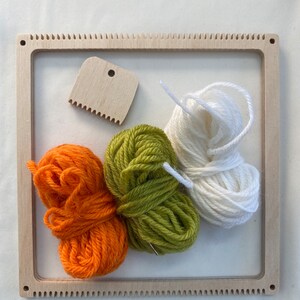 May include: A wooden loom with three balls of yarn: orange, green, and white. A wooden tool with a handle and teeth is also included.