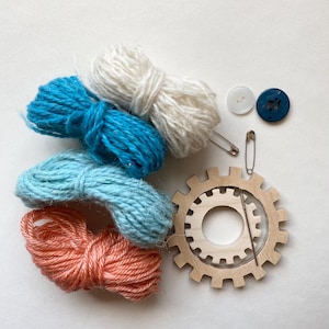 orange and teal yarn, wooden flower looms, needle and buttons