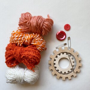 orange yarn, wooden flower looms, needle and buttons