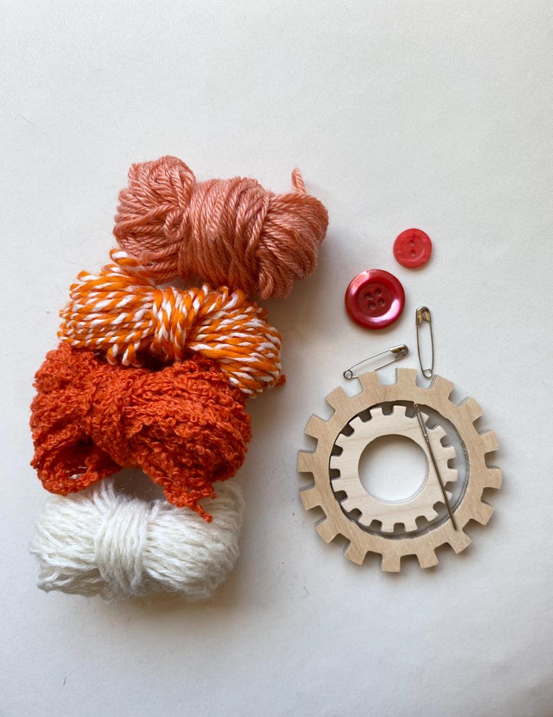 orange yarn, wooden flower looms, needle and buttons