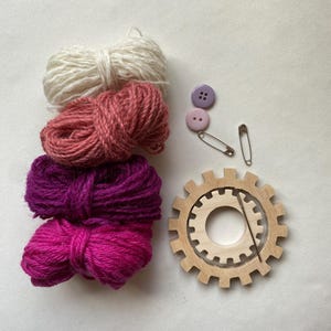 pink yarn, wooden flower looms, needle and buttons