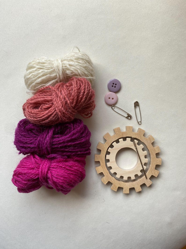pink yarn, wooden flower looms, needle and buttons